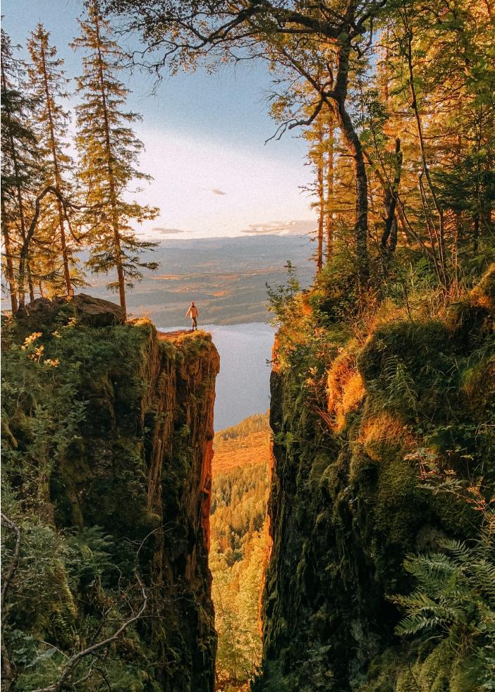 Person hiking with mountains and water around.